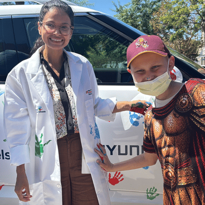 Brian, a 9-year-old patient at the Jonathan Jaques Children’s Cancer Institute, leaves his handprint on the white coat of Bhavita Patel, M.D., as part of the Hyundai Hope on Wheels Handprint Ceremony, a tradition that honors the journeys of children affected by cancer.