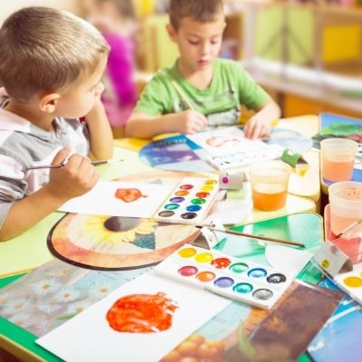 children playing with art supplies in classroom setting.