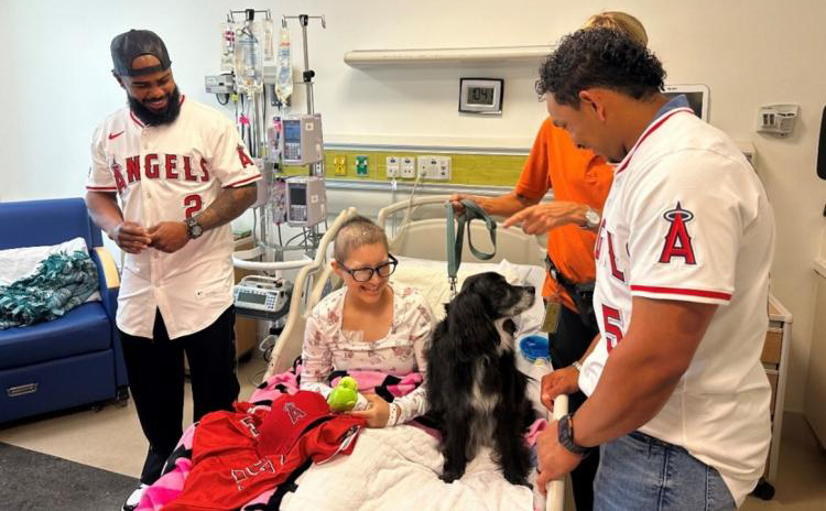 Angels’ infielder Luis Rengifo and outfielder Gustavo Campero share a heartwarming moment with 13-year-old Melinda Espinoza and one of Miller Children’s & Women’s Hospital’s beloved therapy dogs during their visit. The players brought smiles and joy to the young patients, making their hospital stay brighter and more memorable.