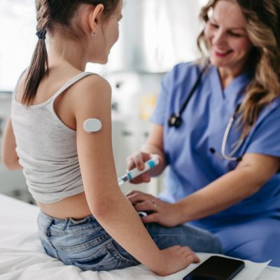 Doctor providing insulin to young girl in clinic office with type 1 diabetes.