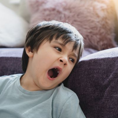Little boy yawning at home.