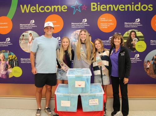Professional football kicker, Cameron Dicker, stands with Girl Scouts Audrey Beck, Ava Ewing and Charley Berman and Rita Goshert, director, Cherese Mari Laulhere Child Life Program, Miller Children’s & Women’s Hospital, as the students deliver sensory toy bags to Miller Children’s & Women’s Emergency Department.