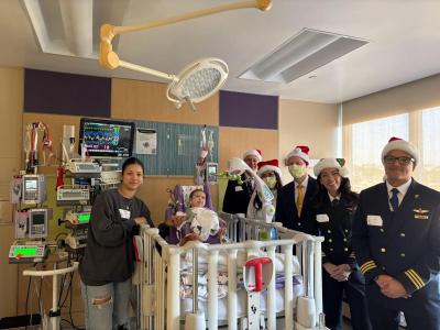 Seven-month-old Samuel and his mother share a tender moment with the festive Pilots for Kids crew during their visit to Miller Children’s & Women’s Hospital.