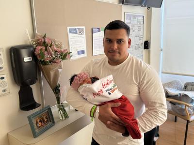 Fernando holding his baby girl, Fernanda in a giant red holiday stocking for the first time