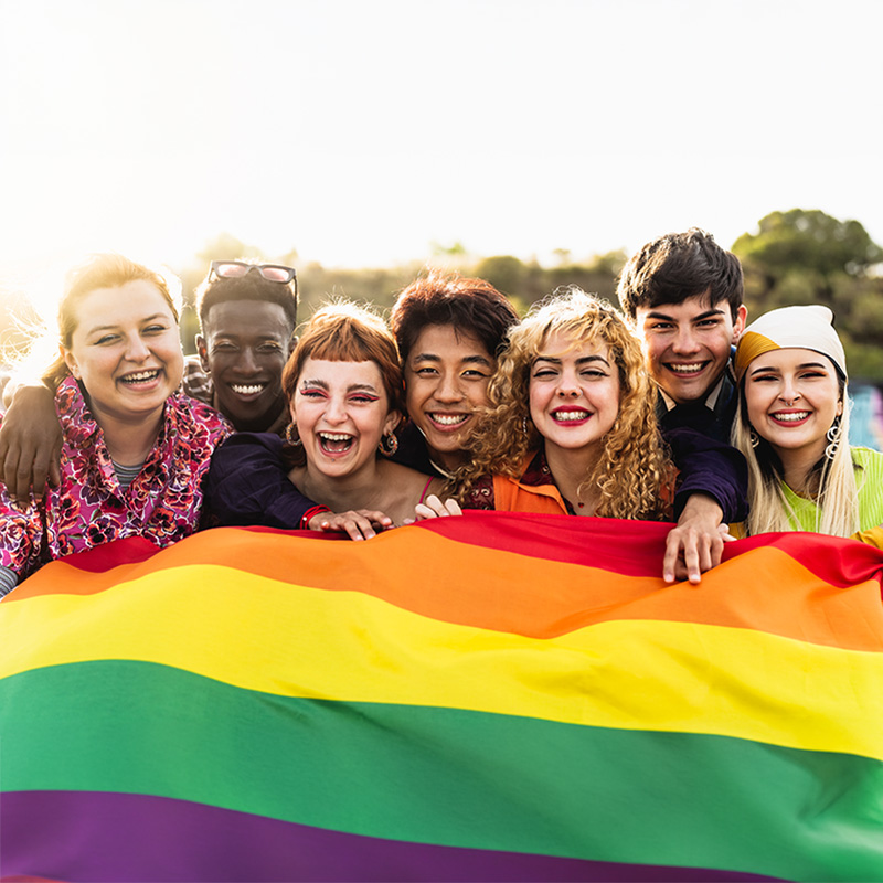 a diverse group of teenager holding a rainbow flag