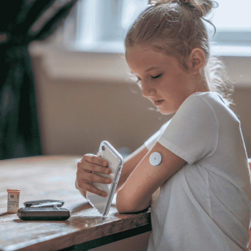 Young girl checking her blood sugar monitor. 